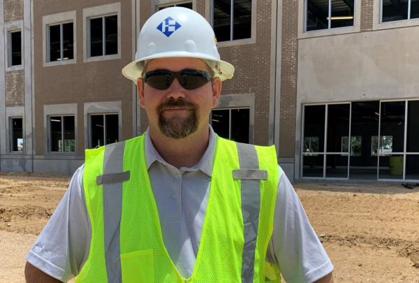 欧洲杯开户app's Superintendent Sonny Carter posing on a job site wearing a hard hat and safety vest.